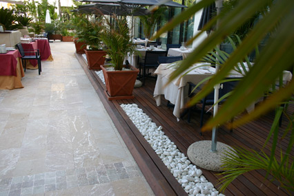 Vista parcial de terraza de restaurante.Realizada dentro de un jardin de Hotel.La Madera de IPE y el bolo blanco son los materiales empleados.